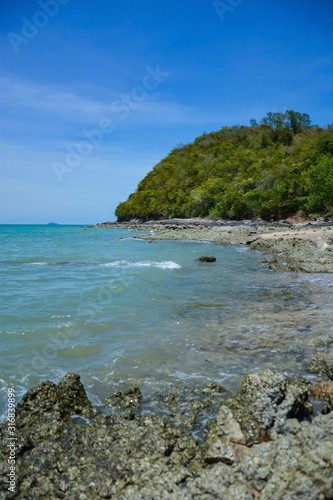 Beautiful rock beach with sea ocean and mountain blue sky landscape background,An island in the sea with beaches, rocks and turquoise water in the hot summer sun of Thailand.