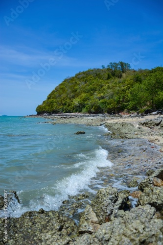 Beautiful rock beach with sea ocean and mountain blue sky landscape background An island in the sea with beaches  rocks and turquoise water in the hot summer sun of Thailand.