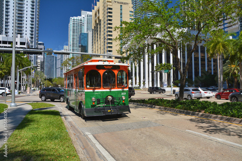 Canvas Print Green trolley goes on Downtown Miami street.