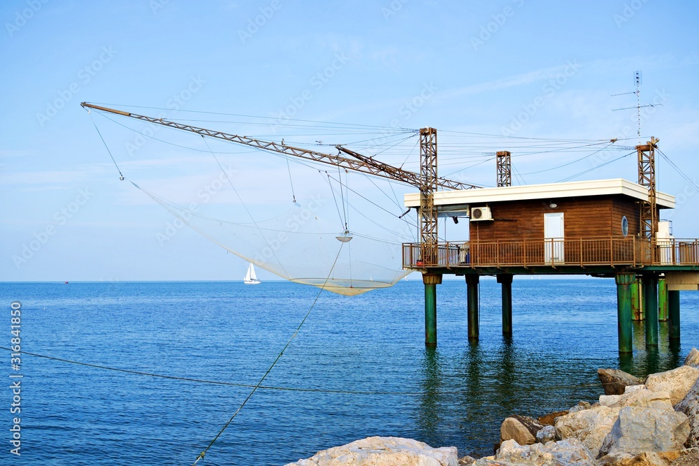 Fototapeta premium caratteristiche capanne da pesca sul molo di Porto Garibaldi nel Mare Adriatico nel comune di Comacchio in provincia di Ferrara in Italia