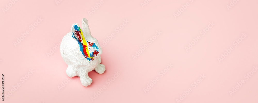 easter rabbit with color strokes on a  pink background, a card for the Easter holidays, panoramic image with space for text