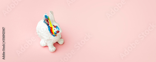 easter rabbit with color strokes on a pink background, a card for the Easter holidays, panoramic image with space for text