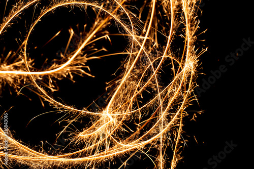 Abstract pattern of sparks and bright light beams of Golden color on a black background