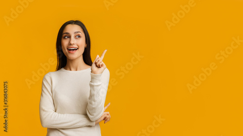 Young Brunette Woman Pointing Finger Up, Having Idea Over Yellow Background photo