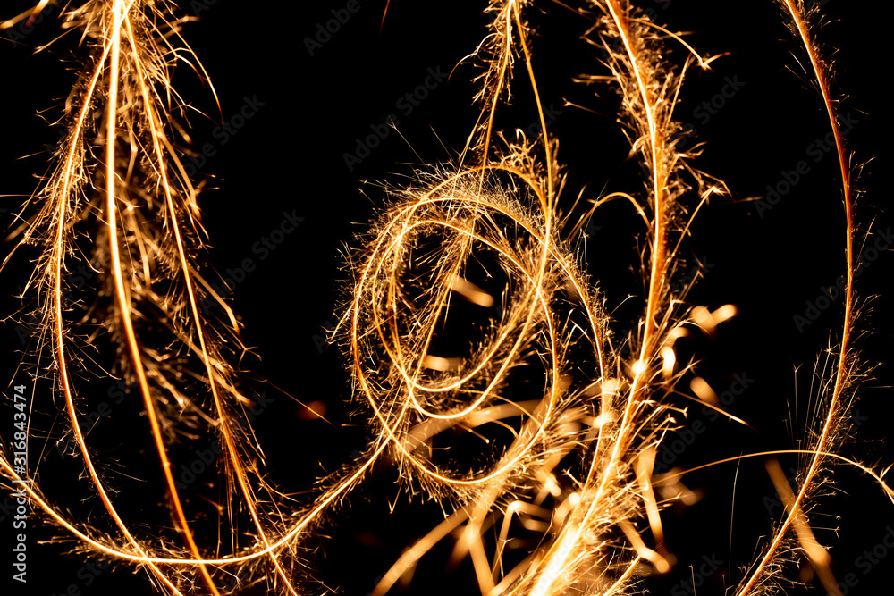 Abstract pattern of sparks and bright light beams of Golden color on a black background