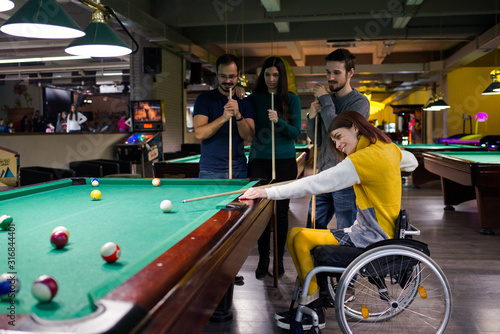 Disabled girl in a wheelchair playing billiards