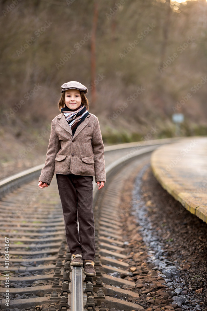 Fototapeta premium Adorable boy on a railway station, waiting for the train