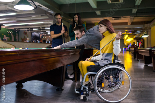 Disabled girl in a wheelchair playing billiards