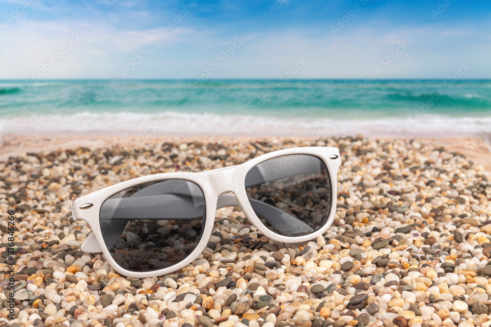 Sun goggles lie on the beach by the sea.