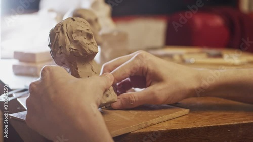 Young artist sculpting bust of woman from real young woman using Plasticine (non-drying clay)