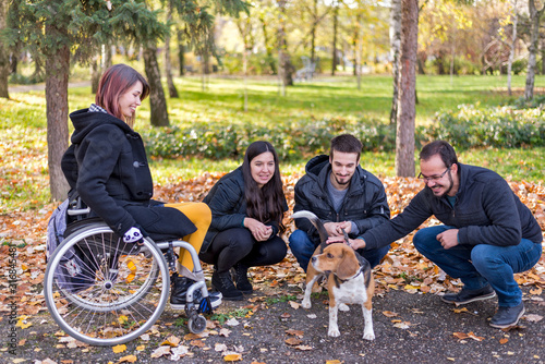 Disabled girl in a wheelchair with friends in the park