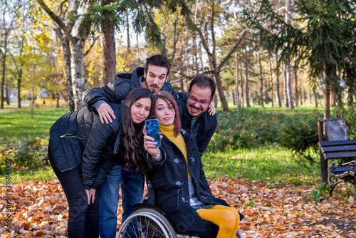Disabled young woman taking selfie with her friends in the park