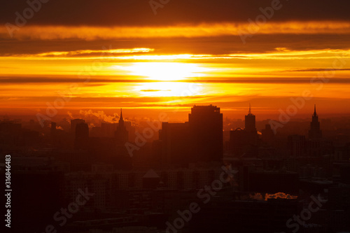 Sunrise over the city. Aerial view of Moscow  silhouettes of buildings in downtown with colorful lighting sunrise sky and soft clouds. Factories pipe  of which there are smoke. Rising sun