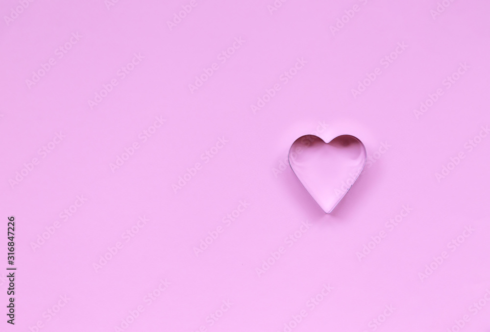Metal baking dish in the form of a heart on a purple background