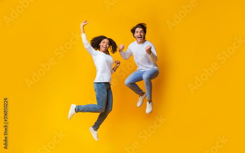 Cheerful girl and handsome guy jumping in air, having fun together