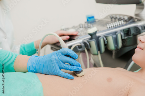 Female doctor working with an ultrasound scanner examining patient stomach.