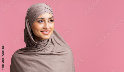 Canvas Print Attractive muslim woman in hijab looking away over pink background