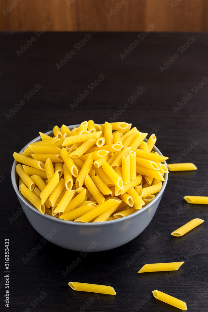 black background with italian raw penne or pasta in bowl with copy space black background with italian raw penne or pasta in bowl with copy space