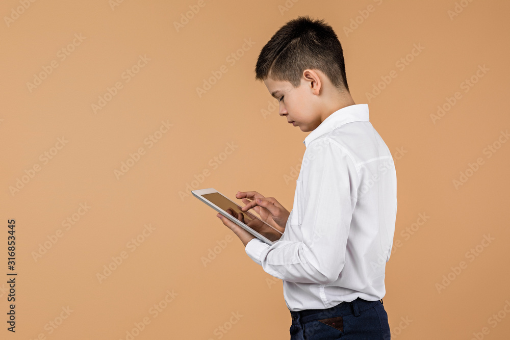 Little boy using tablet on light yellow studio background. space for text. Little boy using tablet on light yellow studio background. space for text.