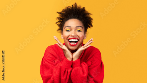 Happy afro woman screaming and touching cheeks © Prostock-studio