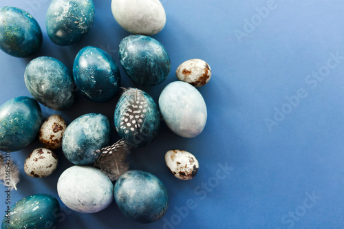 Beautiful group ombre blue Easter eggs with quail eggs and feathers on a blue background. Easter concept
