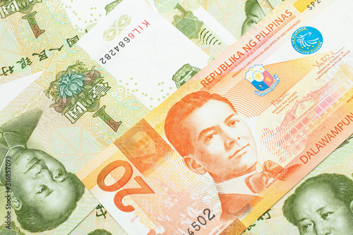 An orange twenty piso bank note from the Philippines with Chinese one yuan bills close up in macro