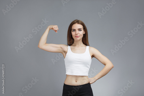 woman shows her muscular arms over gray background