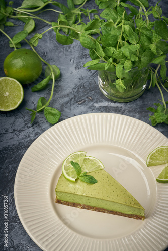Slice of raw green cheesecake with lime and mint  decorated slice of lime. Healthy organic summer dessert pie.