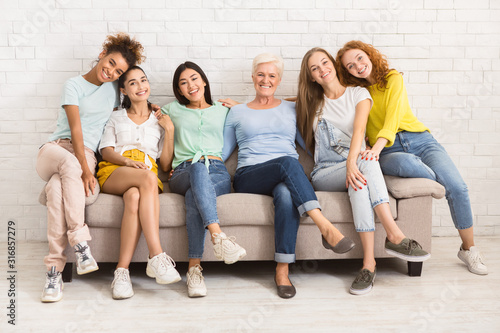 Women Of Different Age Sitting On Sofa Smiling Indoor