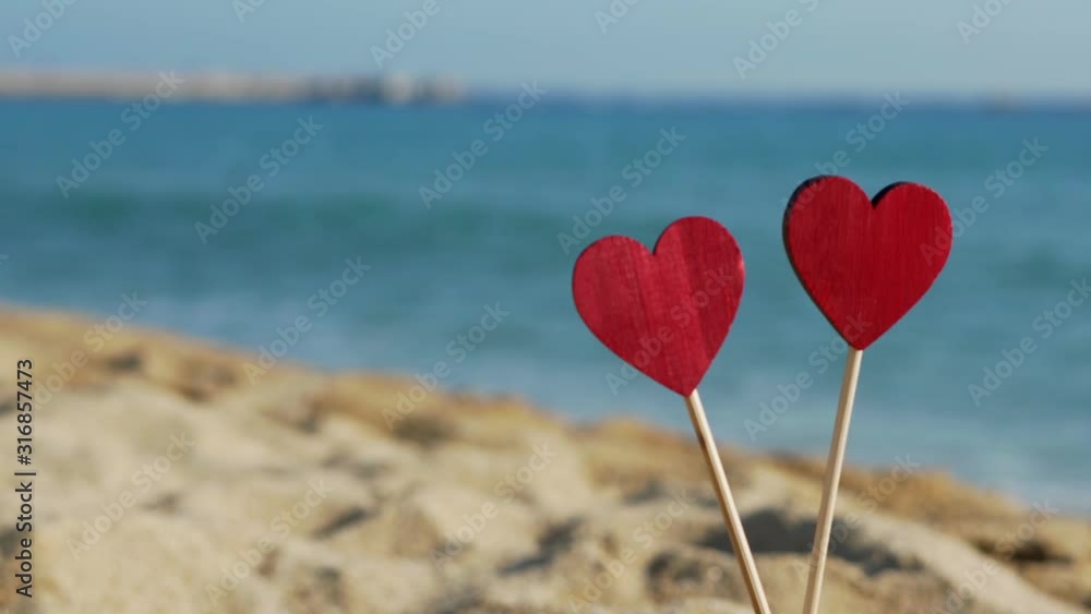 beautiful wooden hearts in the sand on a background of sea waves. beautiful wooden hearts in the sand on a background of sea waves.