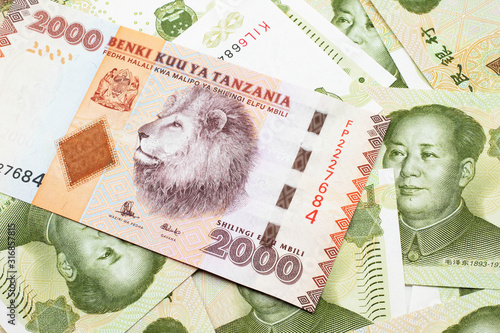 A close up image of a two thousand Tanzanian shilling bank note on a background of Chinese one yuan bank notes photo