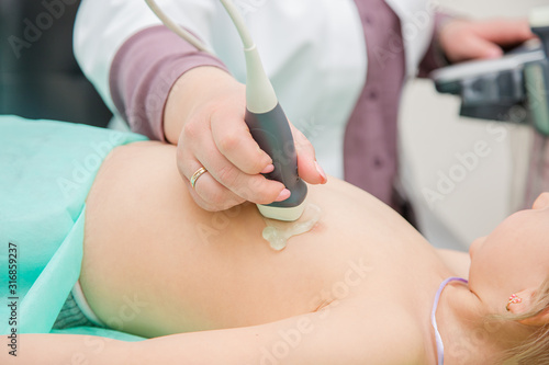 Female doctor working with an ultrasound scanner examining a heart area.