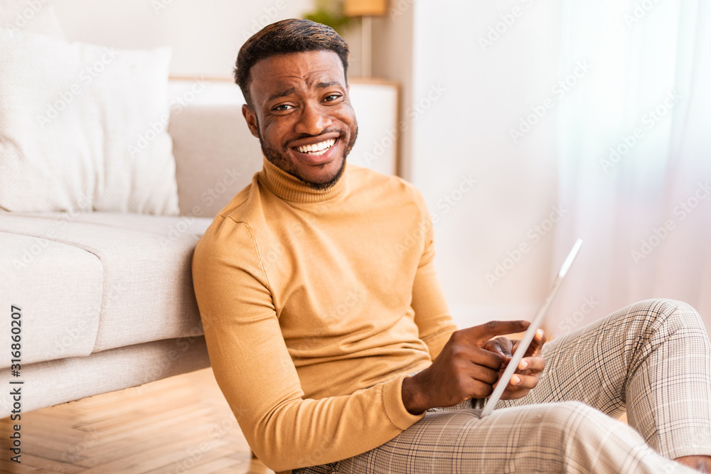Afro Man Using Tablet Smiling Sitting On Floor At Home Afro Man Using Tablet Smiling Sitting On Floor At Home