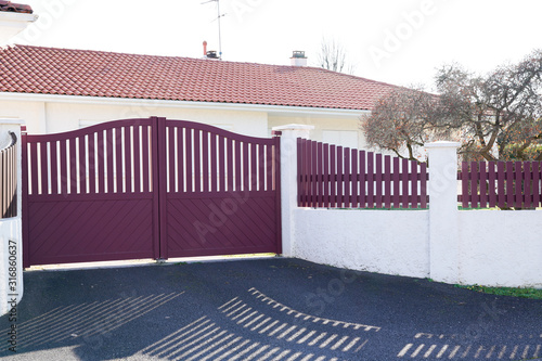 Canvas Print red metal driveway entrance gates set in modern new house