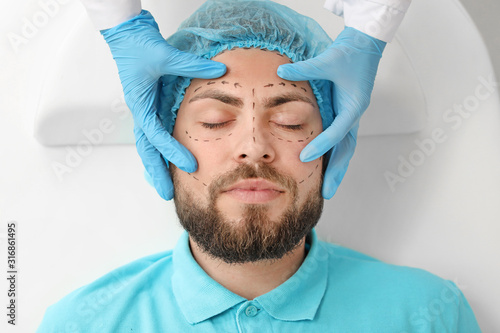Plastic surgeon examining y...