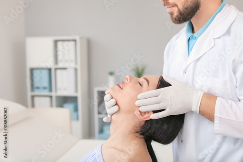 Plastic surgeon examining y...