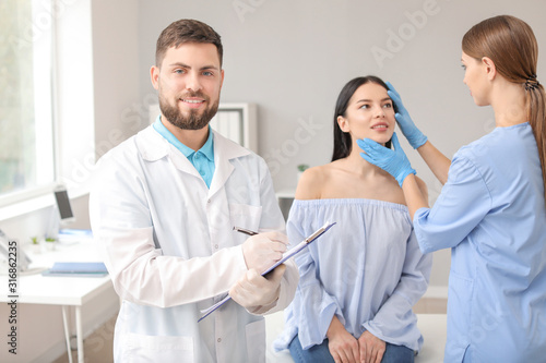 Male plastic surgeon with assistant and patient in clinic