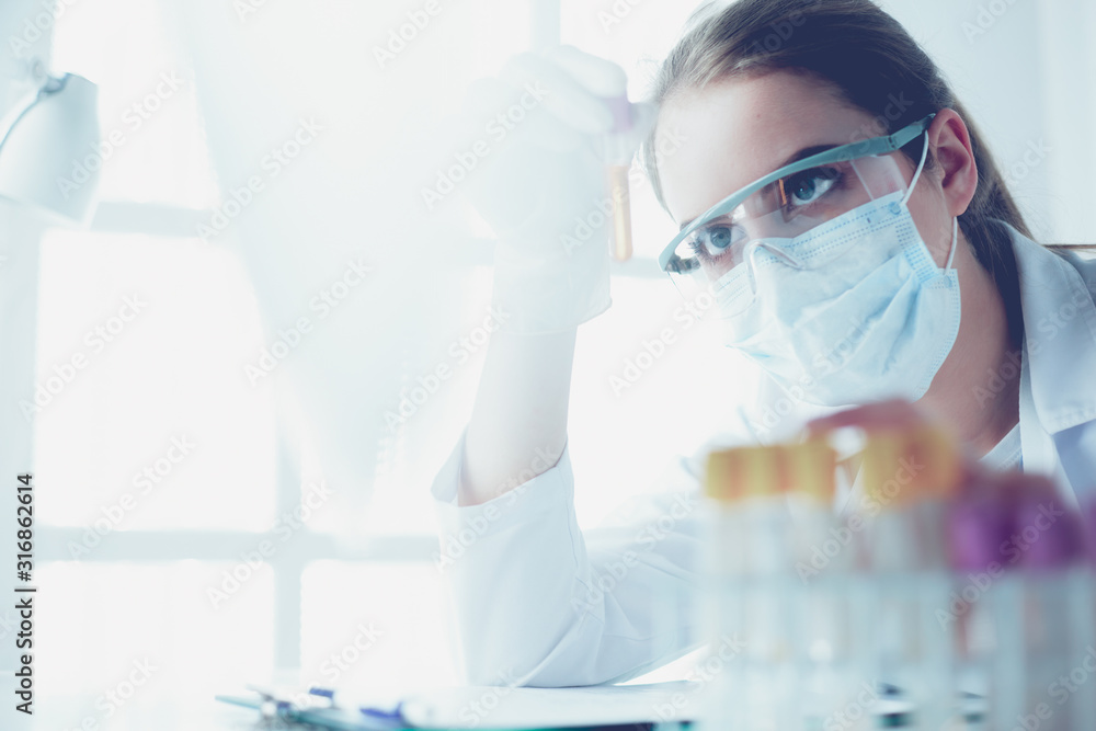 Portrait of pretty female laboratory assistant analyzing a blood sample at hospital - obrazy, fototapety, plakaty 