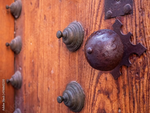 Nice old iron knob on an old wooden door with many veins surrounded by deterrent skewers