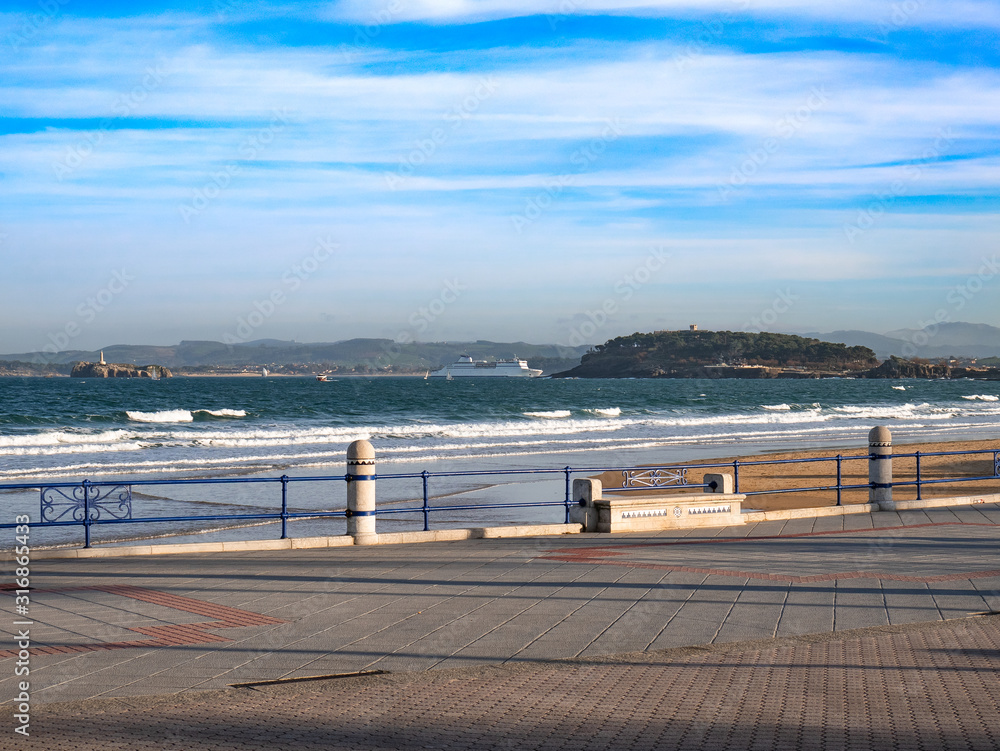 View from the promenade of Santander while a ferry enters the bay with the Magdalena Palace and the lighthouse in the background
