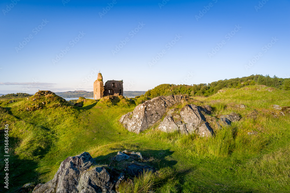 Rocky landscape and Royal Castle of Tarbert at sunset light. Terbert, Scotland.