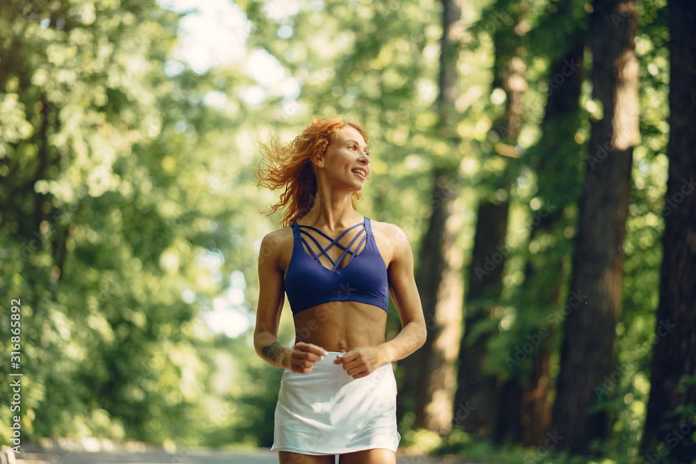 Girl training. Woman in a sports shorts. Redheads girl in a summer park Girl training. Woman in a sports shorts. Redheads girl in a summer park