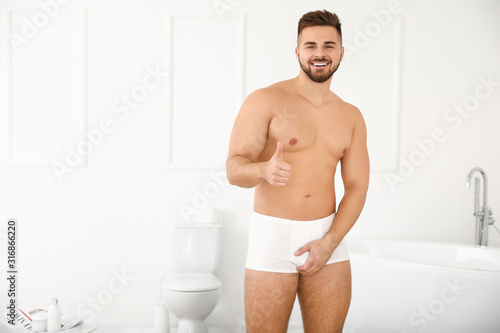 Young man without urologic disease showing thumb-up in bathroom