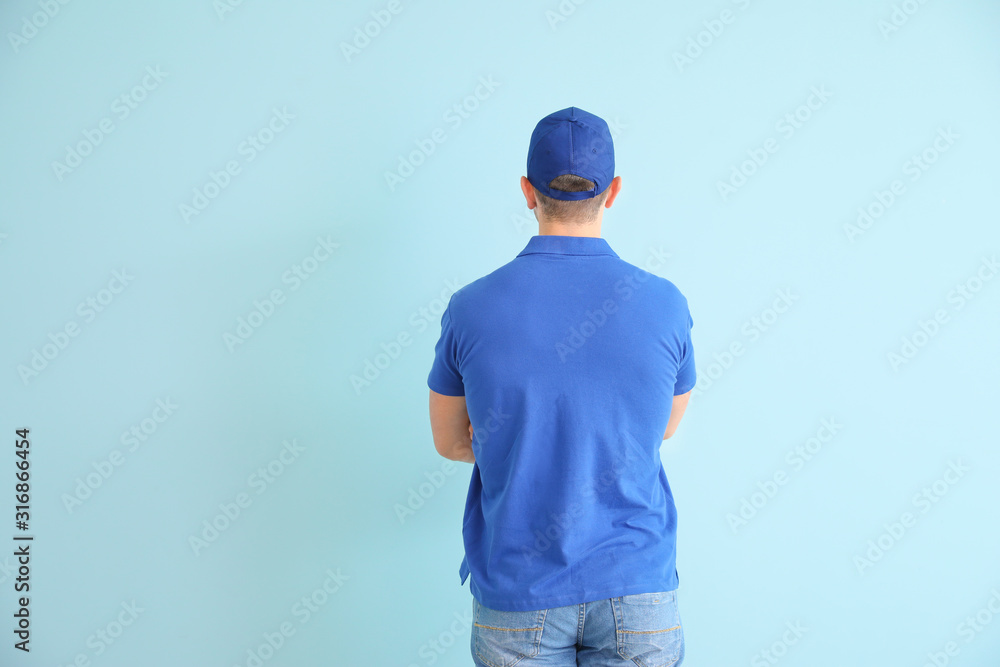 Handsome delivery man on color background, back view Handsome delivery man on color background, back view