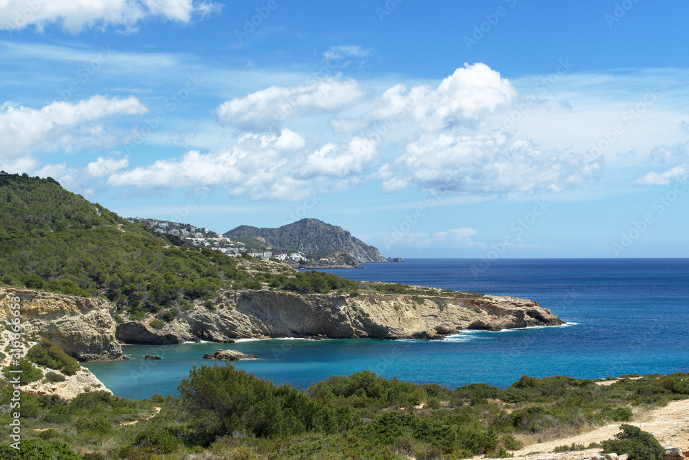 Rocky sea coast with clean blue water, cloudy sky and city view. Ibiza island, Spain Rocky sea coast with clean blue water, cloudy sky and city view. Ibiza island, Spain