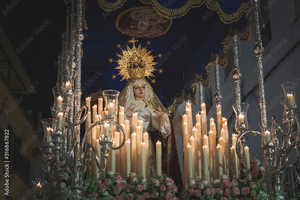 Virgen Maria in procession in Marbella at the holy week , candles an throne at night