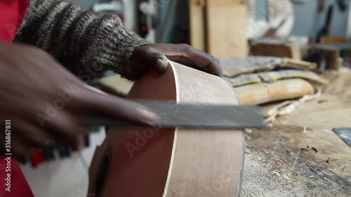 Craftman making guitar using chisel on wood photo