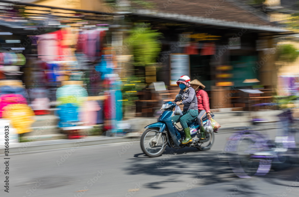 Panning motion shot of commuter in Hoi An, Vietnam.