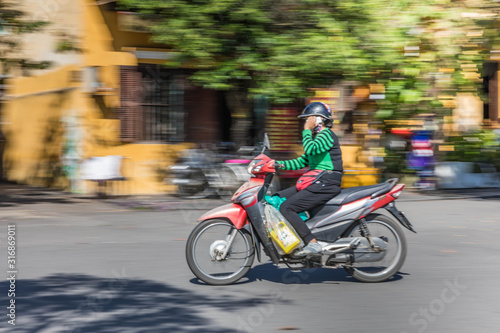 Panning motion shot of commuter in Hoi An, Vietnam.