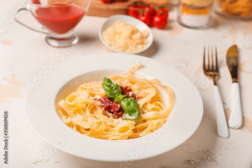 Plate with tasty pasta and tomato sauce on white table